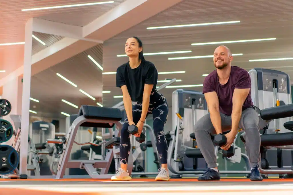 girl fitness trainer and bodybuilder doing exercises with dumbbells in the gym group training